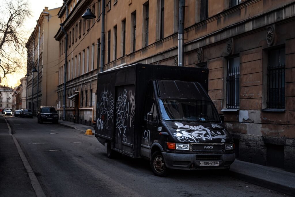 A graffiti-covered truck parked on a dimly lit urban street at twilight, capturing a rustic city atmosphere.