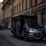 A graffiti-covered truck parked on a dimly lit urban street at twilight, capturing a rustic city atmosphere.
