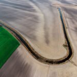 High-angle drone shot showcasing vast agricultural fields and winding waterway.