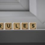 Identical small square shaped cubes with RULES title and numbers on white windowsill near window in house in daylight