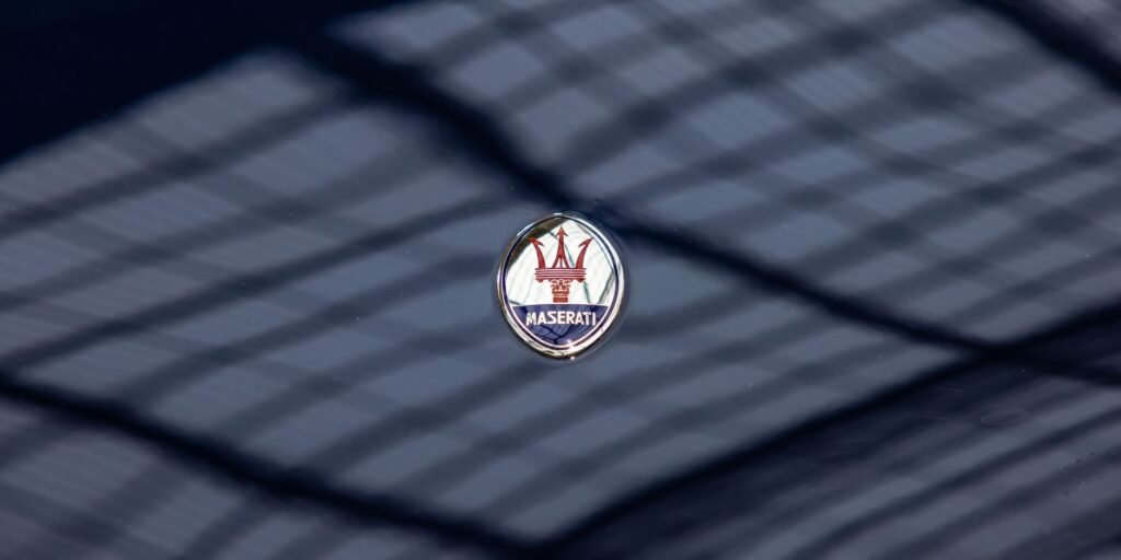 Maserati logo emblem on a dark glossy car surface with reflections, focus on luxury branding.