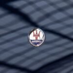 Maserati logo emblem on a dark glossy car surface with reflections, focus on luxury branding.