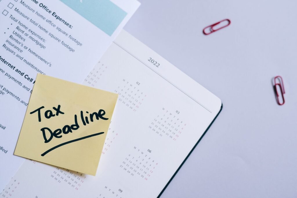 A sticky note highlights tax deadline on a calendar alongside documents, emphasizing financial planning.