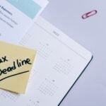A sticky note highlights tax deadline on a calendar alongside documents, emphasizing financial planning.
