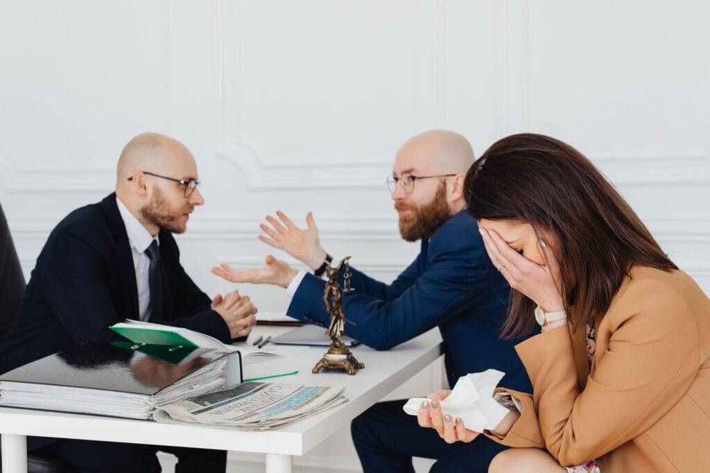 A lawyer mediates an emotional settlement discussion with a distressed couple in a legal office.