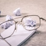 Eyeglasses and crumpled paper on notepad, symbolizing creative brainstorming process.