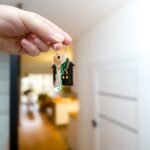 A hand holding house keys inside a modern apartment, symbolizing new property ownership or rental.