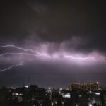 A striking lightning storm illuminates the night sky over an urban cityscape, capturing the power of nature.