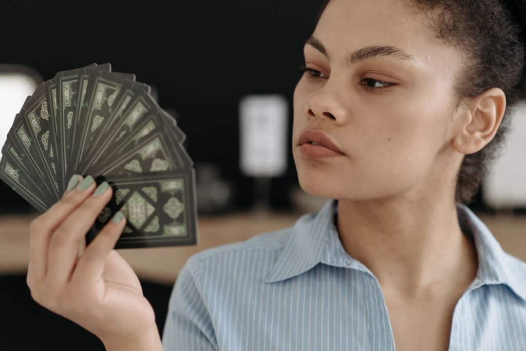 Focused young woman examining a fan of tarot cards, exploring divination.