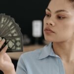 Focused young woman examining a fan of tarot cards, exploring divination.